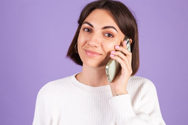 Jeune brune en pull décontracté blanc isolé sur mur violet