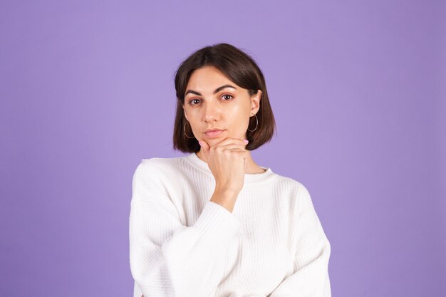 Jeune brune en pull décontracté blanc isolé sur mur violet