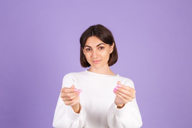 Jeune brune en pull décontracté blanc isolé sur mur violet