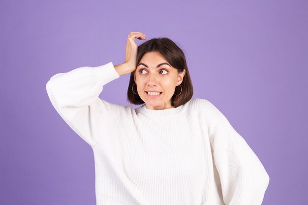 Jeune brune en pull décontracté blanc isolé sur mur violet