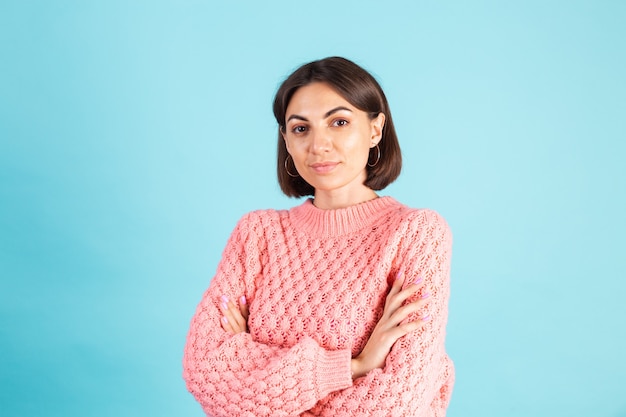 Jeune brune en pull rose isolé sur mur bleu