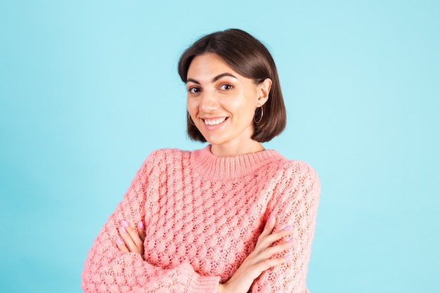 Jeune brune en pull rose isolé sur mur bleu