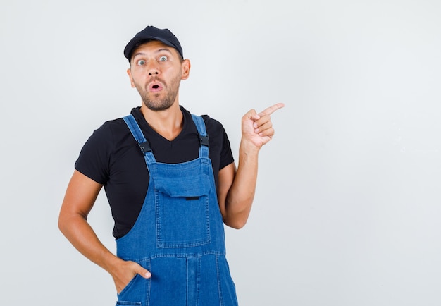 Jeune chargeur pointant vers le côté en uniforme et à la peur, vue de face.