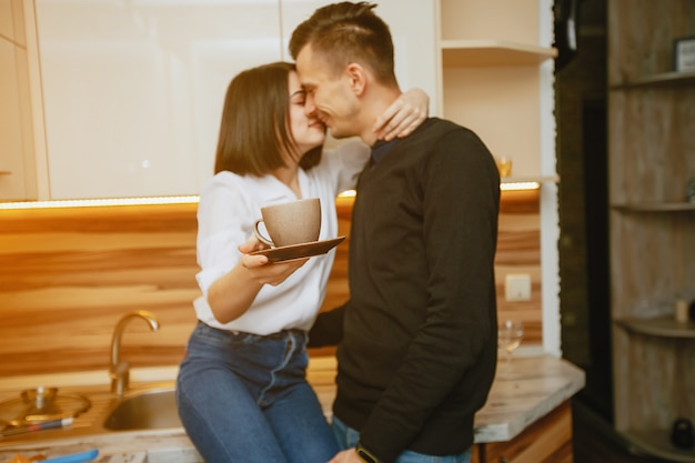 Jeune et charmant couple charmant debout dans la cuisine avec un café