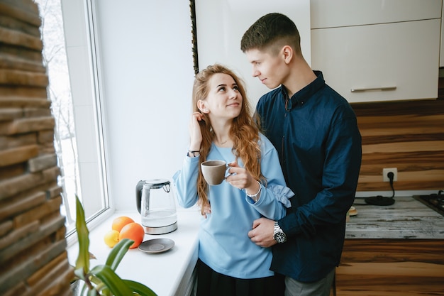 jeune et charmant couple charmant debout près de la fenêtre dans la cuisine