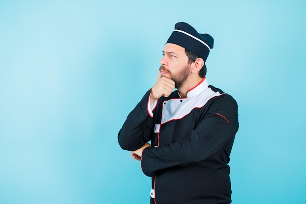 Le jeune chef pense en levant les yeux et en mettant la main sur le menton sur fond bleu