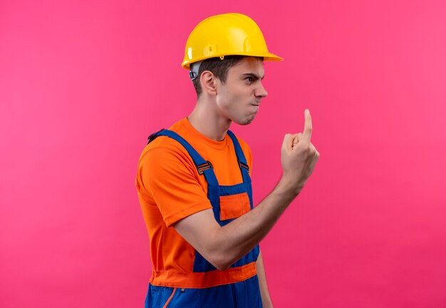 Jeune constructeur homme portant un uniforme de construction et un casque de sécurité gronde quelqu'un avec sumb