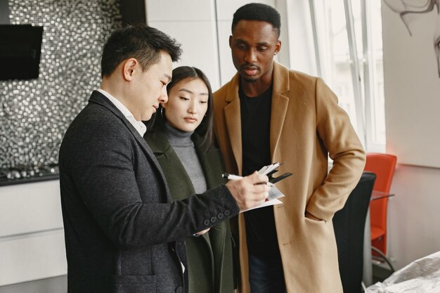 Jeune couple achetant une nouvelle maison. Femme asiatique et homme africain. Signature des documents à la nouvelle maison.