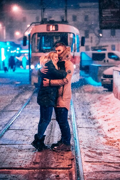 Jeune couple adulte sur la ligne de tram enneigée