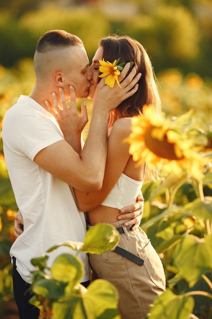 Jeune couple aimant s'embrasse dans un champ de tournesol. Portrait de couple posant en été dans le champ.