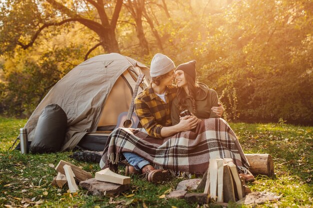 Jeune couple aimant de touristes se détendre près du feu dans la nature