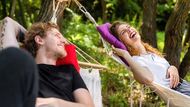 Photo gratuite jeune couple allongé sur des hamacs se regardant en souriant