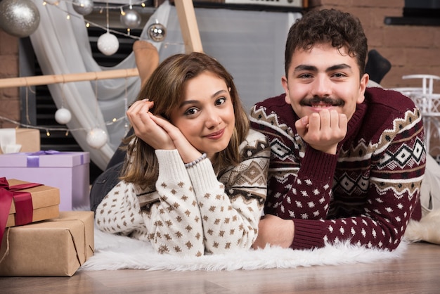 Jeune couple allongé sur le sol à l'intérieur de Noël.