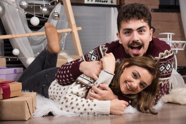 Jeune couple allongé sur le sol à l'intérieur de Noël.