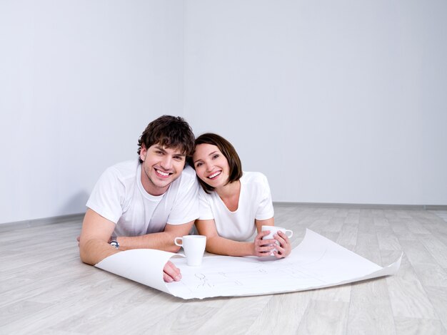 Jeune couple allongé sur le sol avec plan de nouvelle chambre