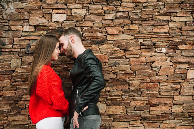 Jeune couple amoureux devant le mur de briques