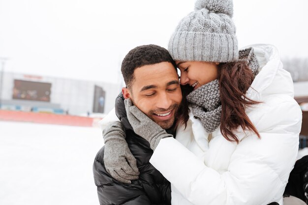 Jeune couple d'amoureux heureux étreindre et patiner à la patinoire