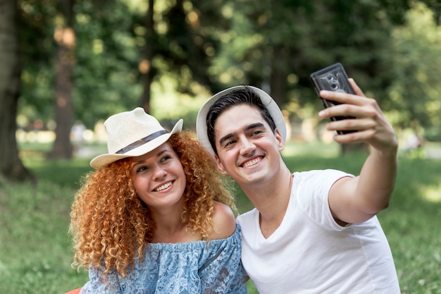 Jeune couple d'amoureux en plein air prenant un selfie