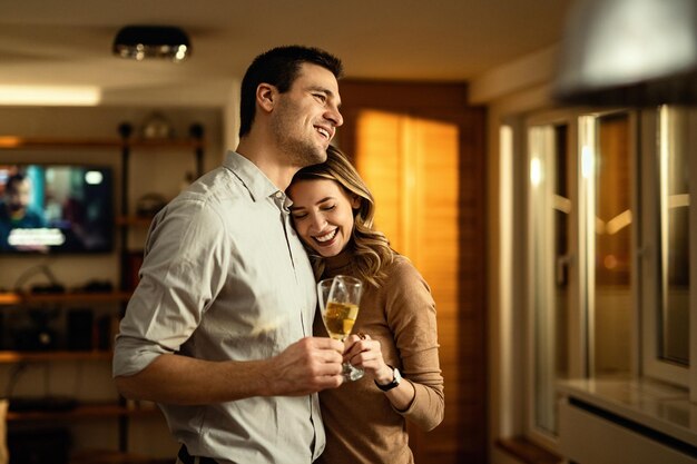 Jeune couple amoureux portant un toast au champagne en se tenant debout dans le salon