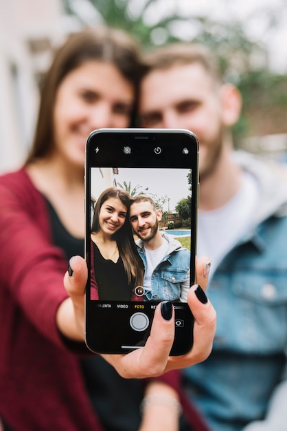 Jeune couple amoureux prenant selfie dans le jardin