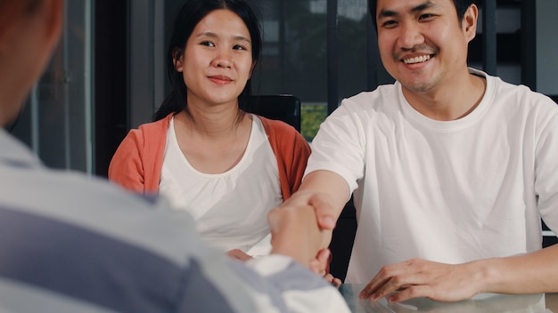 Un Jeune Couple Asiatique Enceinte Signe Des Documents Contractuels à La Maison, Une Famille Japonaise Consulte Un Conseiller Financier En Immobilier, L’achat D’une Nouvelle Maison Et La Négociation Avec Un Courtier Dans Le Salon Le Matin.