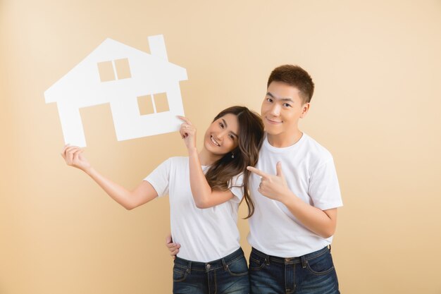 Jeune couple asiatique heureux présentant les symboles de la maison