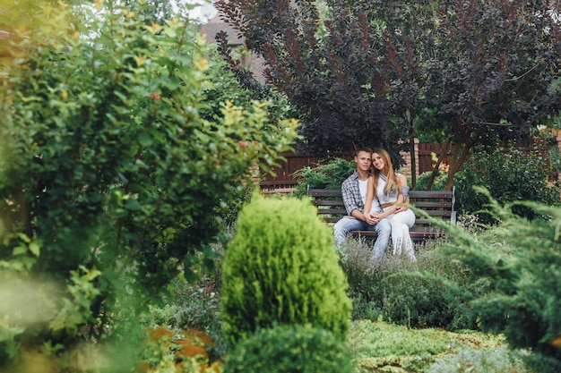 Jeune couple assis sur un banc dans le parc et regardant à l'avant