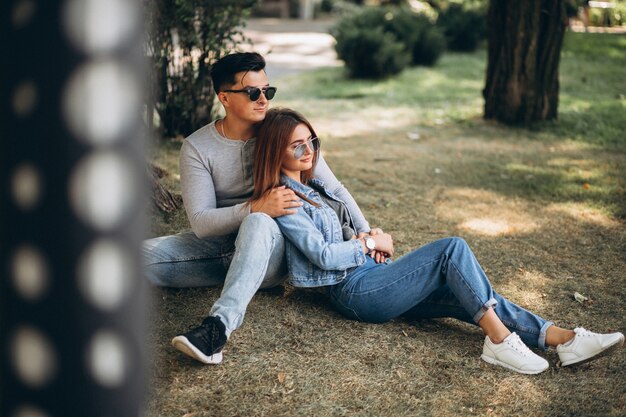 Jeune couple assis sur l&#39;herbe dans le parc