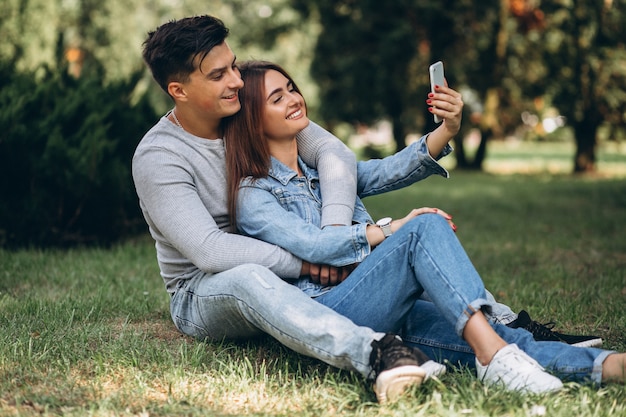 Jeune couple assis sur l&#39;herbe dans le parc