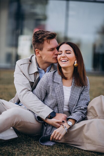 Jeune couple assis sur l&#39;herbe près du bâtiment