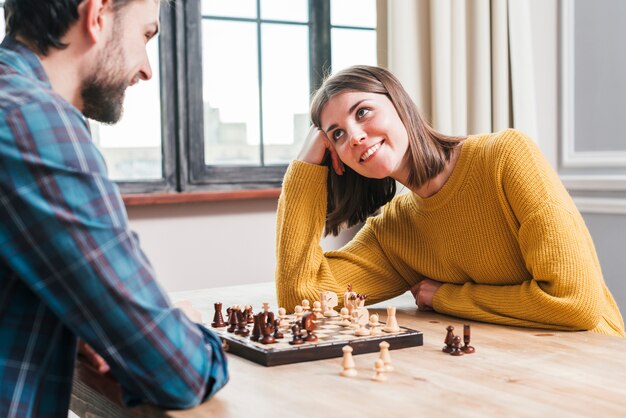 Jeune couple assis à jouer aux échecs à la maison