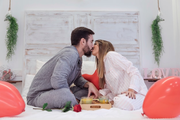 Jeune couple assis sur le lit et s&#39;embrasser