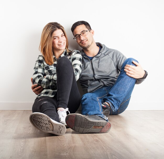 Jeune couple assis sur le plancher en souriant