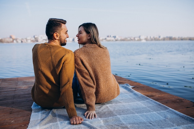 Jeune couple assis sur le pont en bord de rivière