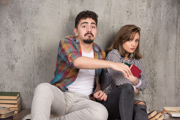 jeune couple assis et prenant un livre l'un de l'autre