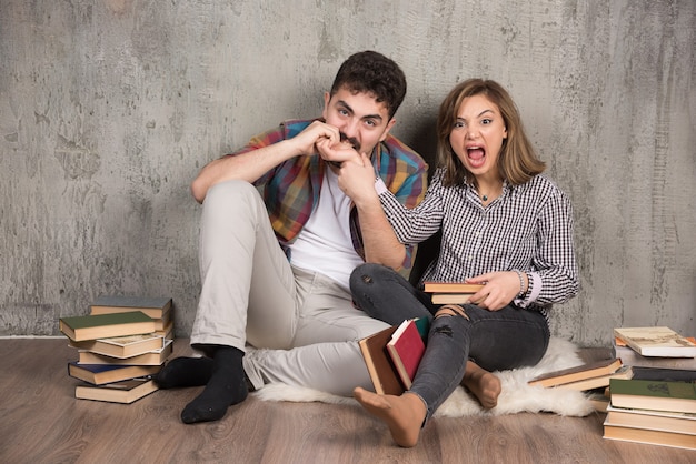 jeune couple assis sur le sol avec des livres