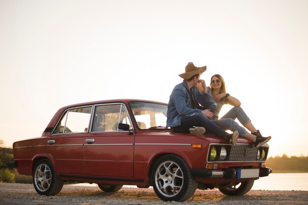 Jeune couple assis sur une voiture vintage