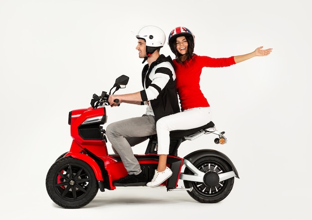 Jeune couple attrayant chevauchant un scooter de moto électrique heureux de s'amuser ensemble