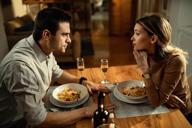 Jeune couple ayant des problèmes dans leur relation et parlant pendant un repas à table à manger