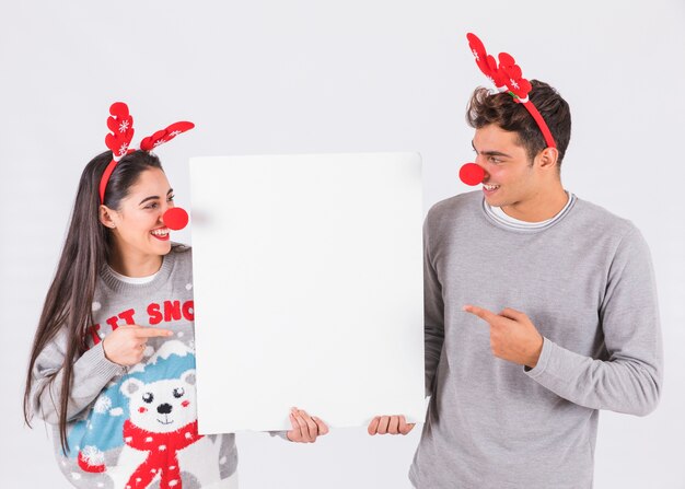 Jeune couple avec bandeaux de bois de cerf et nez drôles tenant la tablette