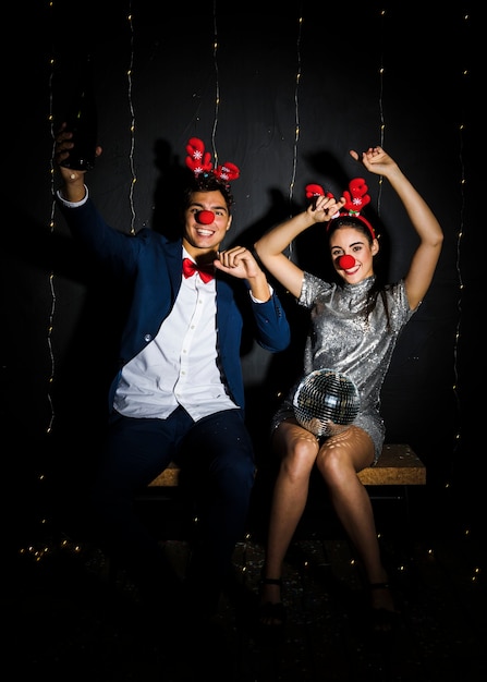 Jeune couple avec bandeaux en bois de cerf et nez rigolo avec boule disco