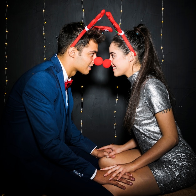 Jeune couple avec bandeaux en bois de cerf rouge et nez rigolo