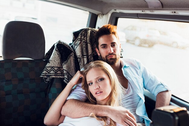 Jeune couple sur la banquette arrière de la voiture