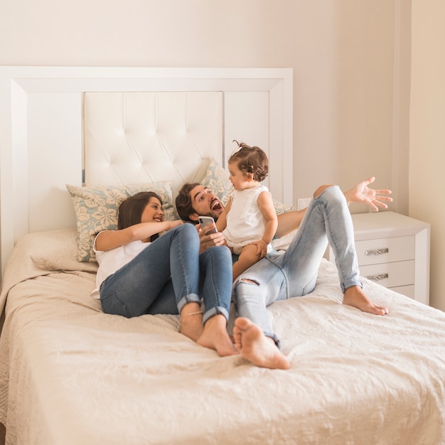 Jeune couple avec bébé sur lit