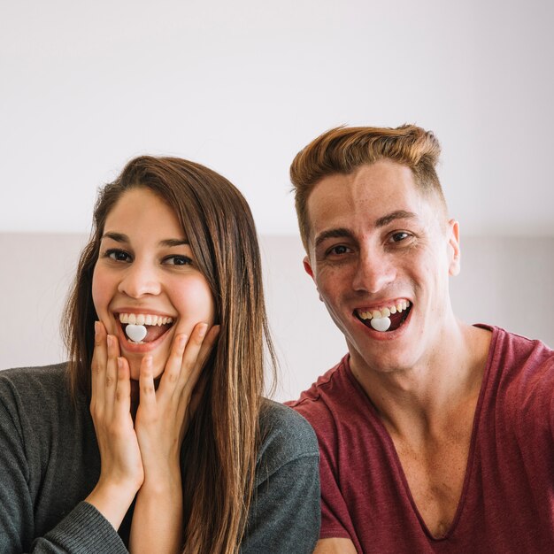 Jeune couple avec des bonbons de coeur dans la bouche