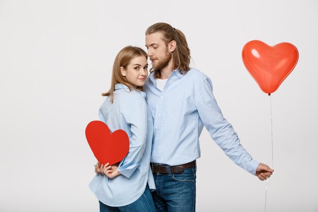 Jeune couple caucasien attactive tenant le ballon et le papier de coeur