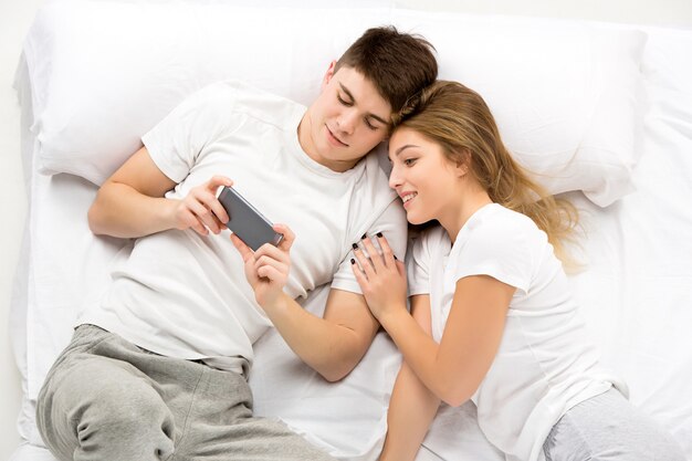 Le jeune couple charmant allongé dans un lit