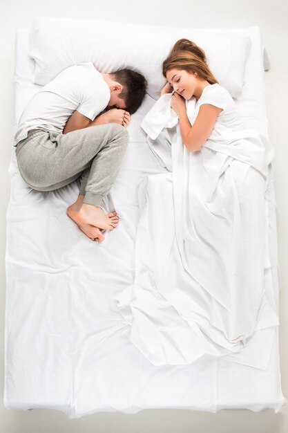 Le jeune couple charmant couché dans un lit blanc, amour lconcept, vue de dessus