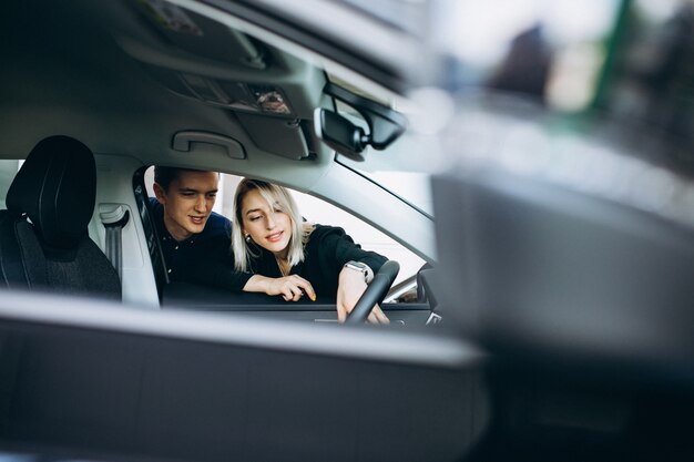 Jeune couple choisissant une voiture dans un salon automobile