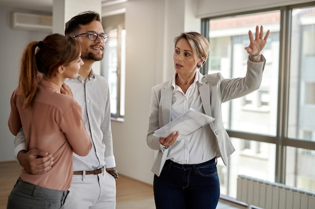 Jeune couple communiquant avec un agent immobilier lors de l'achat de leur nouvelle maison L'accent est mis sur l'agent